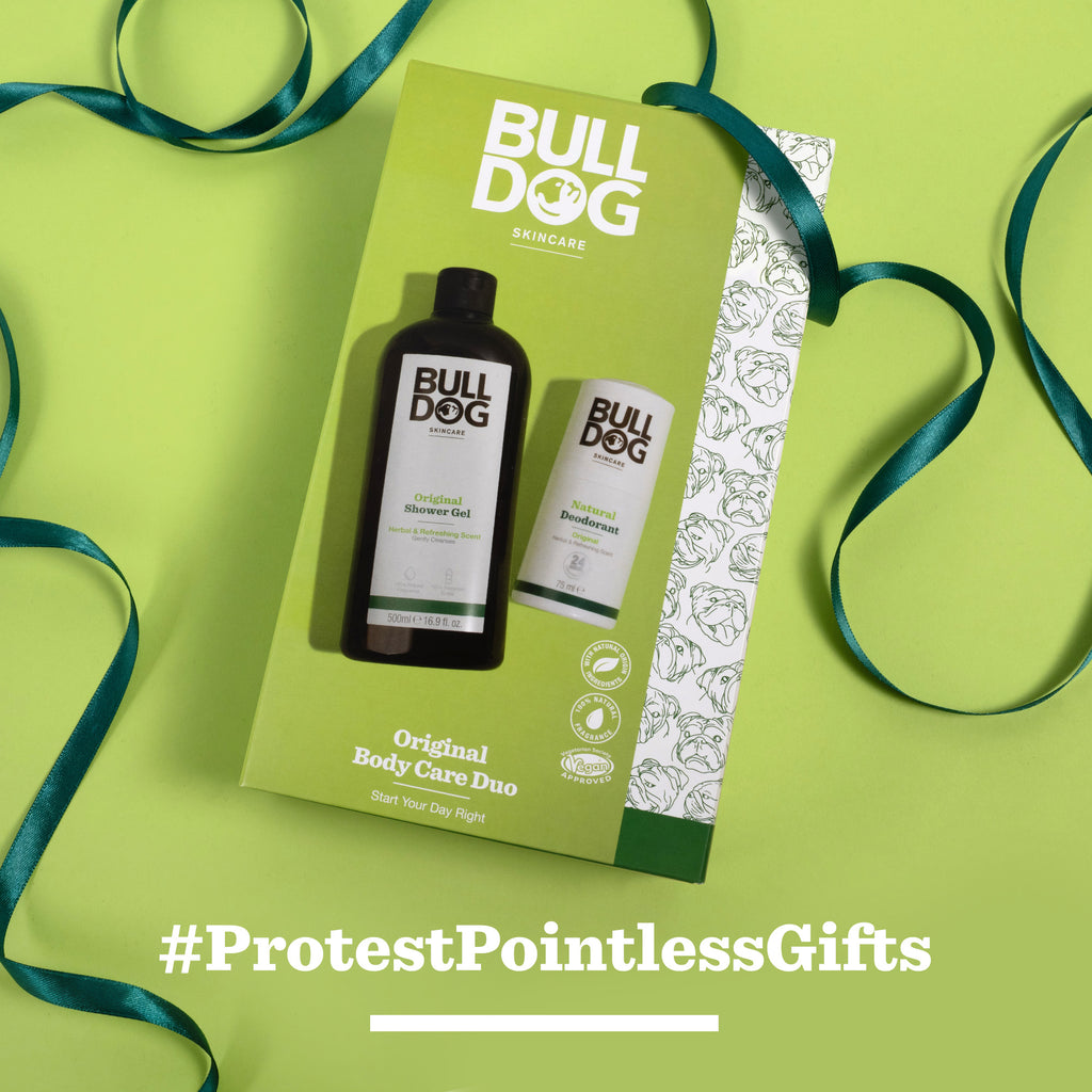 The Original Body Care Duo gift set—perfect for men—rests on a green backdrop with ribbon. The box shows Original Shower Gel and Moisturizer. “#ProtestPointlessGifts” appears in white at the bottom.